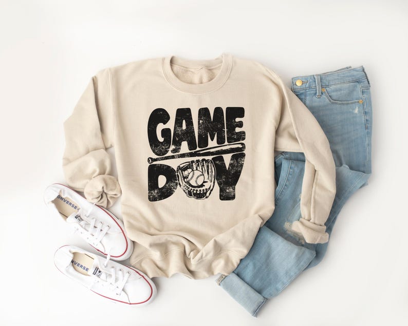 May include: A beige sweatshirt with a black graphic print that says "GAME DAY" with a baseball bat and glove.