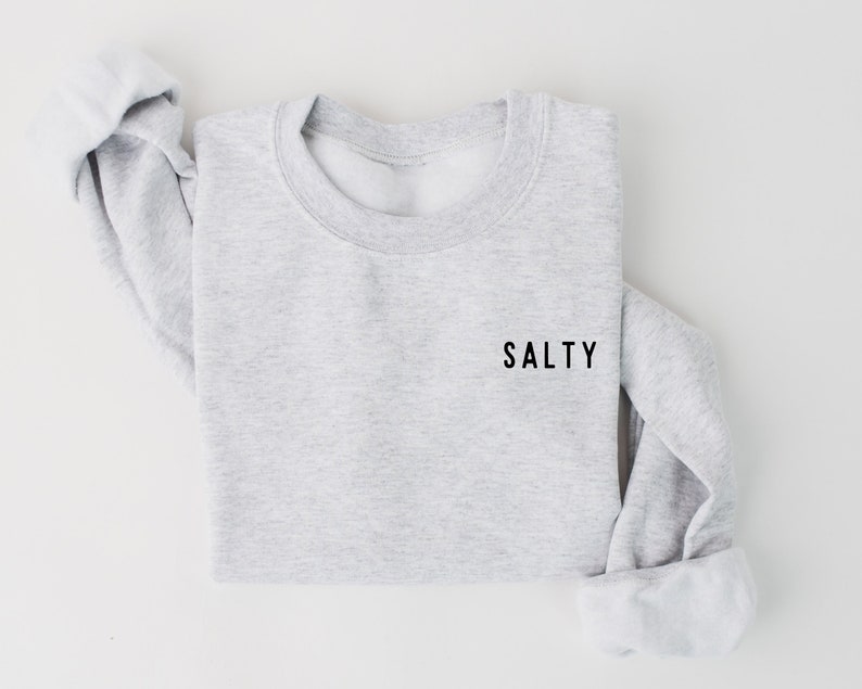 May include: A gray sweatshirt with the word "SALTY" printed in black on the front.