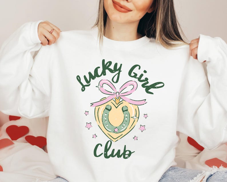 May include: White sweatshirt with a green and pink graphic design that says "Lucky Girl Club" with a horseshoe and a heart.