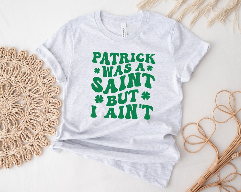 May include: A gray t-shirt with the text "Patrick was a* Saint *but* I ain't" in green.