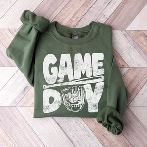May include: A green sweatshirt with a white distressed graphic that says "GAME DAY" with a baseball bat and glove.