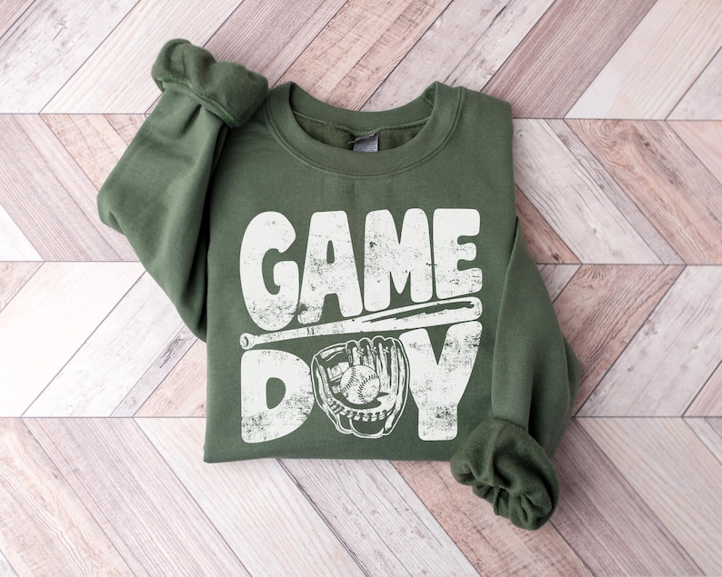 May include: A green sweatshirt with a white distressed graphic that says "GAME DAY" with a baseball bat and glove.