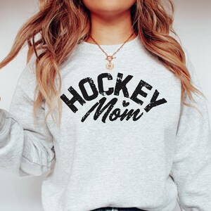May include: A gray sweatshirt with the text "Hockey Mom" in black with a small heart graphic.