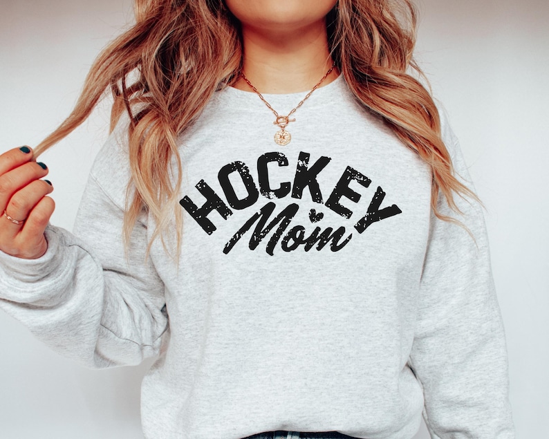May include: A gray sweatshirt with the text "Hockey Mom" in black with a small heart graphic.