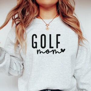 May include: A gray sweatshirt with the text "GOLF mom" in black lettering with a small heart next to the word "mom".