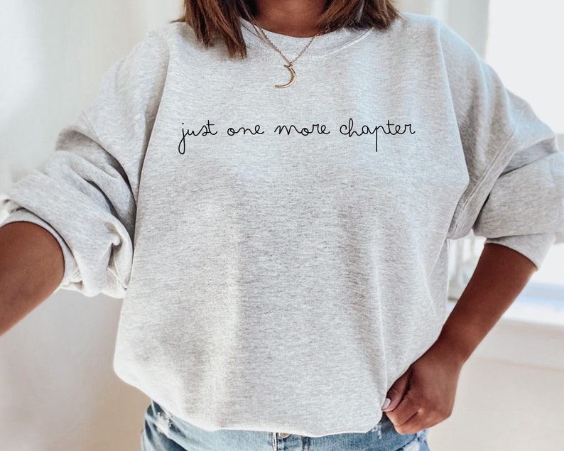 May include: A gray sweatshirt with the text "just one more chapter" written in black cursive.