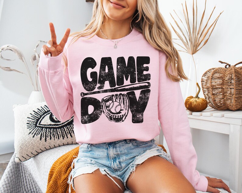 May include: Pink sweatshirt with a black graphic that says "GAME DAY" with a baseball bat and glove.