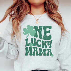 May include: A gray sweatshirt with a green shamrock and the text "One Lucky Mama" in a retro font.