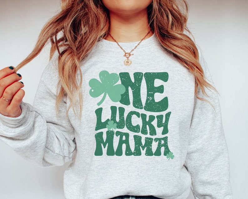 May include: A gray sweatshirt with a green shamrock and the text "One Lucky Mama" in a retro font.