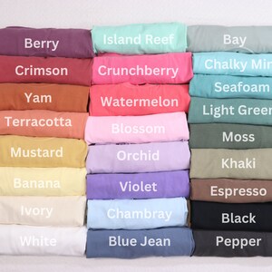 May include: A collection of folded fabric swatches in various colours, including berry, crimson, yam, terracotta, mustard, banana, ivory, white, island reef, crunchberry, watermelon, blossom, orchid, violet, chambray, blue jean, bay, chalky mint, seafoam, light green, moss, khaki, espresso, black, and pepper.