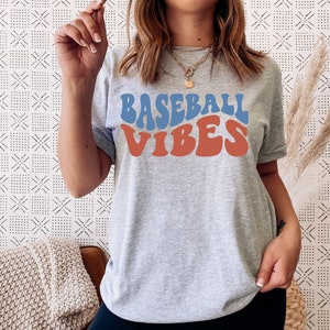 May include: A gray t-shirt with the text "BASEBALL VIBES" in blue and orange retro font.