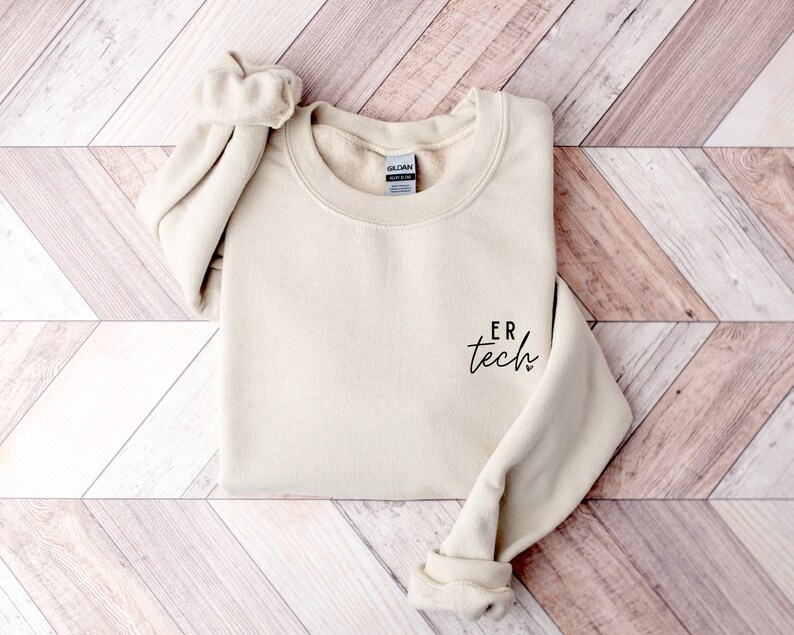 May include: A beige sweatshirt with the text "ER tech" in black script on the left chest.