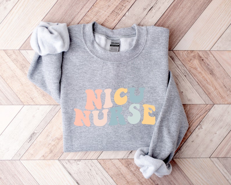 May include: Grey sweatshirt with the words "NICU NURSE" in rainbow coloured letters.