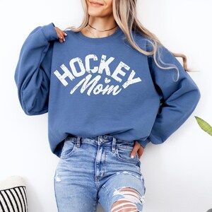 May include: A blue sweatshirt with the text "HOCKEY MOM" in white with a small heart graphic.
