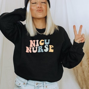 May include: Black sweatshirt with the text "NICU NURSE" in rainbow colours. The text is in a retro font style.