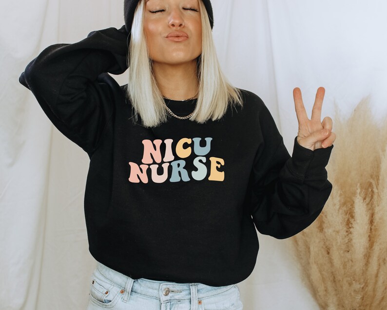 May include: Black sweatshirt with the text "NICU NURSE" in rainbow colours. The text is in a retro font style.