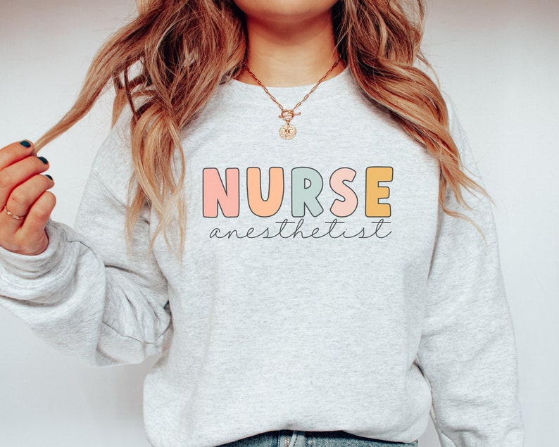 May include: A light gray sweatshirt with the text "NURSE anesthetist" in colorful letters. The letters are outlined in black and have a rounded, playful font.