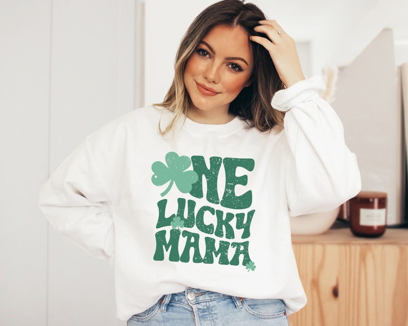 May include: White sweatshirt with a green shamrock and the text "One Lucky Mama" in a retro font.