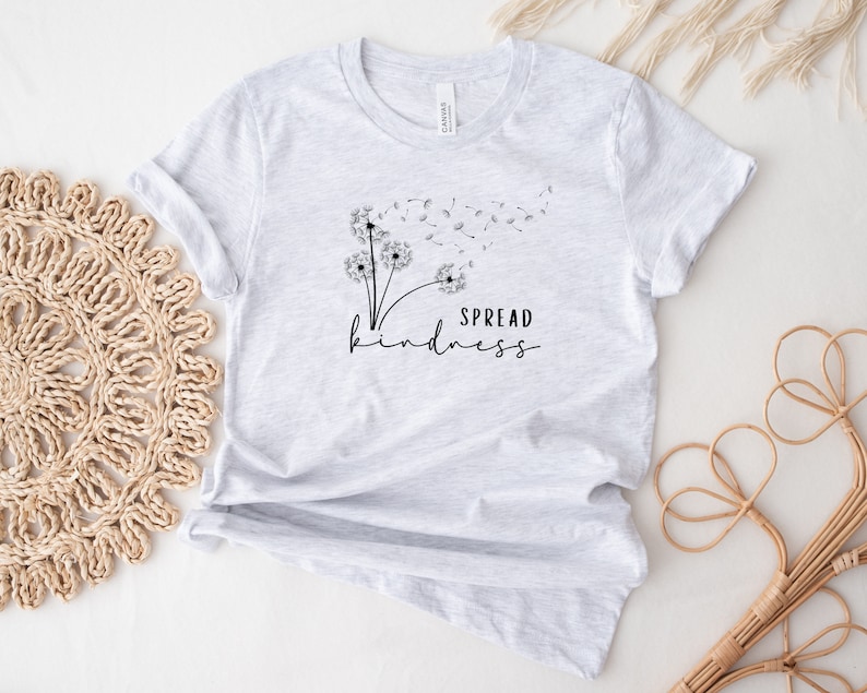 K&ouml;nnte beinhalten: Ein graues T-Shirt mit einer schwarzen L&ouml;wenzahndruck und dem Text "SPREAD kindness".