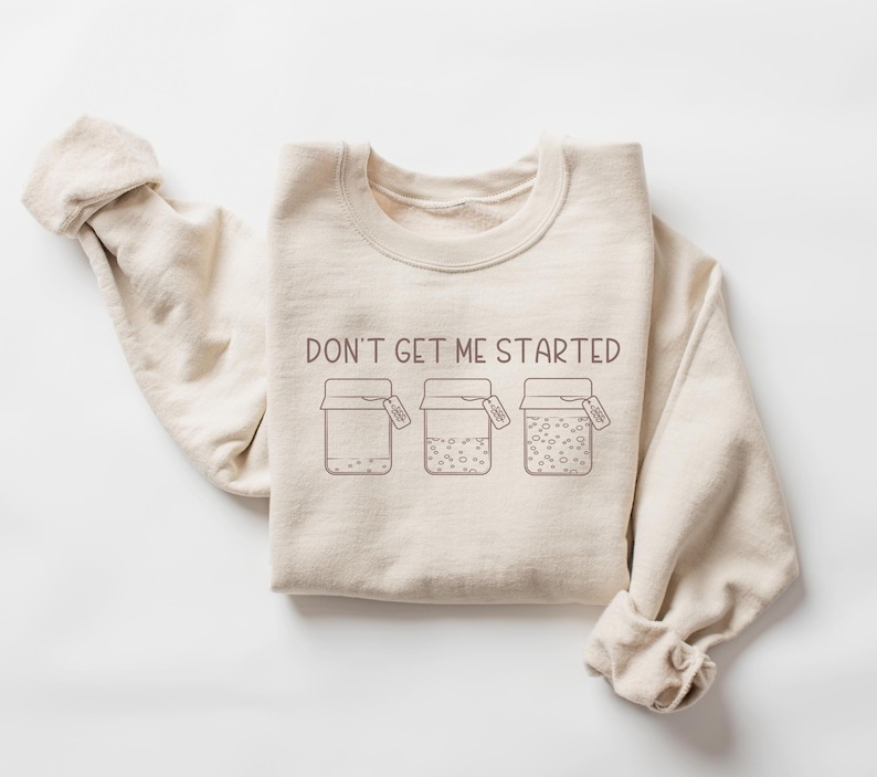 Peut inclure: Un sweat-shirt beige avec le texte "Don't get me started" et un graphique de trois bocaux avec des couvercles. Chaque bocal a une &eacute;tiquette qui dit "Good Vibes Only".