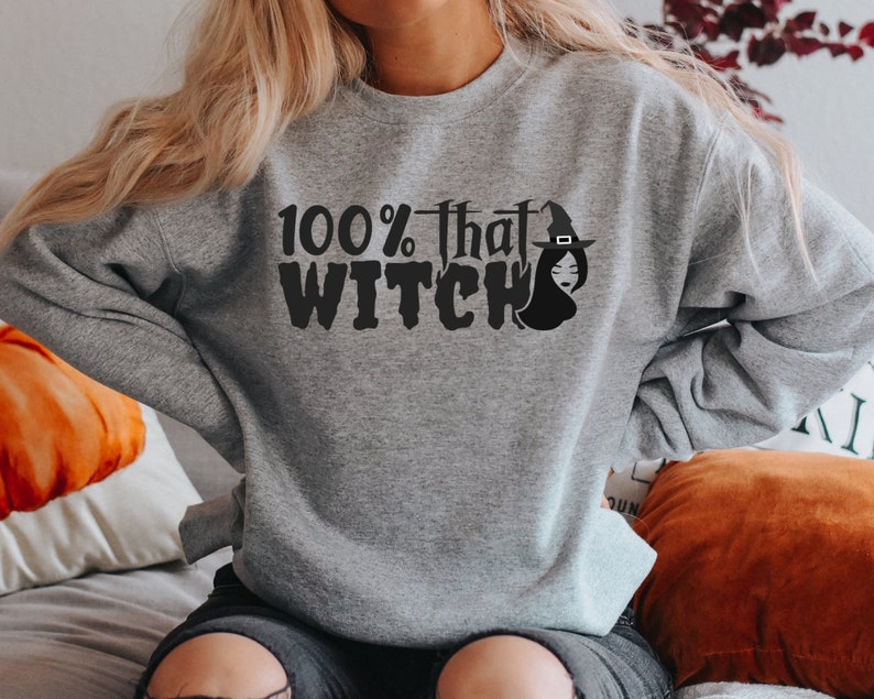 May include: A gray sweatshirt with the text "100% that WITCH" and a black silhouette of a witch wearing a hat.