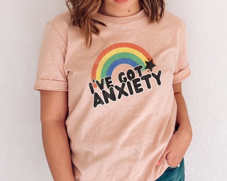 May include: A pink t-shirt with a rainbow and a star graphic. The text on the shirt reads "I've got anxiety".