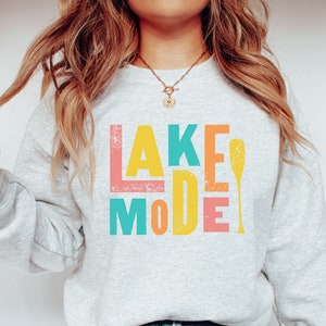 May include: A gray sweatshirt with the text "LAKE MODE" in colorful block letters and a yellow paddle graphic.