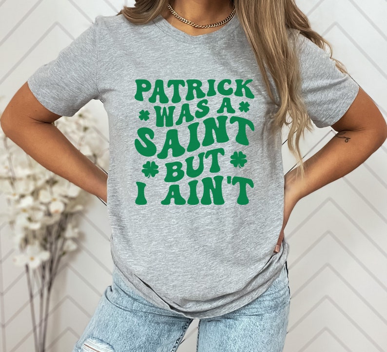 May include: A gray t-shirt with a green graphic that reads "Patrick was a* Saint *but* I ain't".