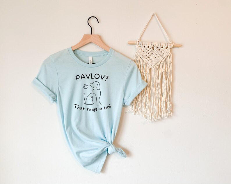 May include: A light blue t-shirt with a black graphic of a dog and the text "Pavlov? That rings a bell."
