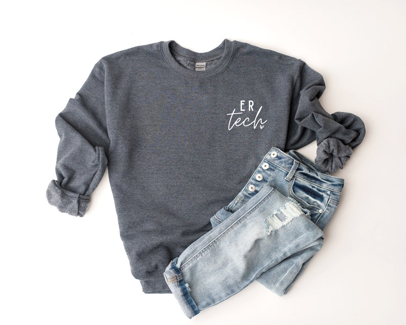 May include: A dark gray sweatshirt with the text "ER tech" in white script on the front. The sweatshirt is paired with light blue denim jeans.