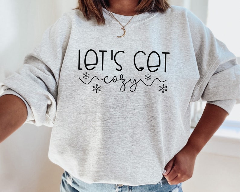 May include: A gray sweatshirt with the text "Let's Get Cozy" in black lettering with snowflake accents.
