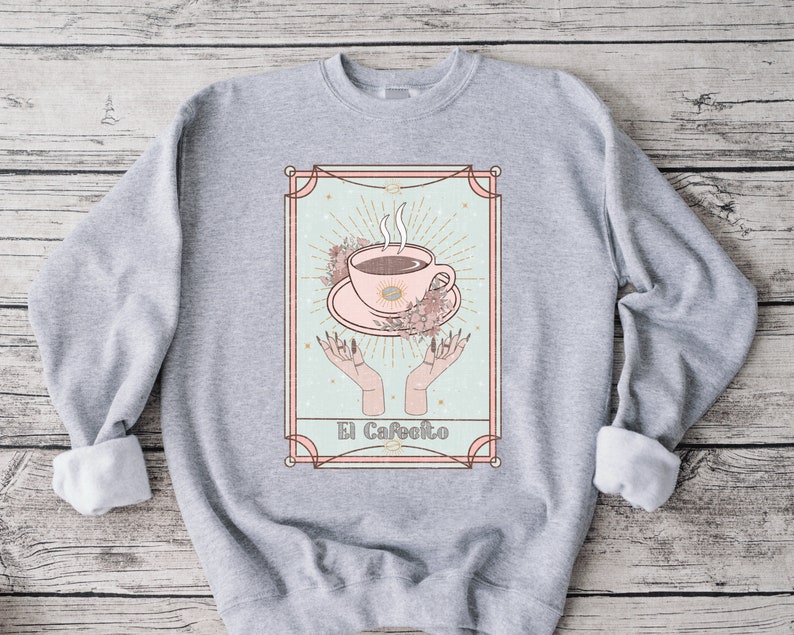 May include: A gray sweatshirt with a graphic print of a coffee cup in a vintage style frame. The text "El Cafeito" is printed below the cup.