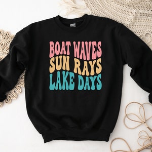 May include: Black sweatshirt with the text "BOAT WAVES SUN RAYS LAKE DAYS" in a retro font with pink, yellow, and blue colors.