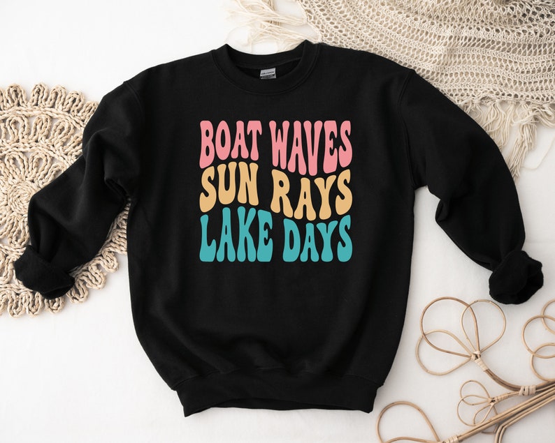 May include: Black sweatshirt with the text "BOAT WAVES SUN RAYS LAKE DAYS" in a retro font with pink, yellow, and blue colors.