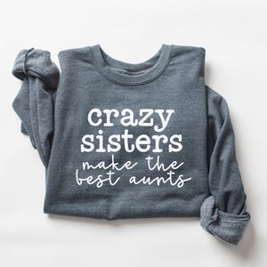 May include: A dark gray sweatshirt with the text "crazy sisters make the best aunts" printed in white.