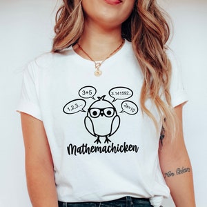 May include: White t-shirt with a black and white illustration of a chicken wearing glasses and thinking about math equations. The text "Mathemachicken" is printed below the chicken.