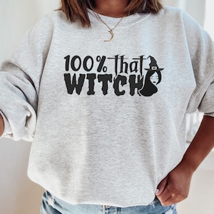 May include: A gray sweatshirt with the text "100% that WITCH" in black with a black silhouette of a witch wearing a hat.