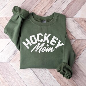 May include: A green sweatshirt with the text "Hockey Mom" in white with a small heart.