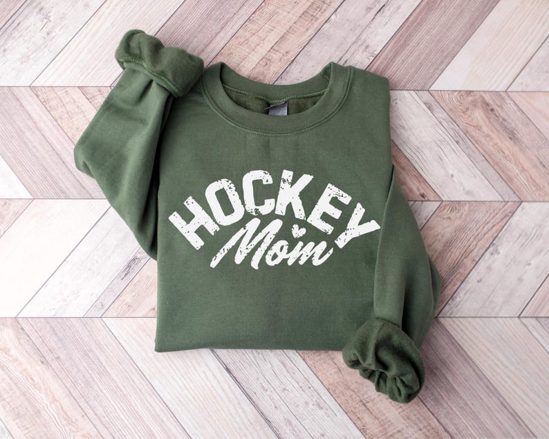 May include: A green sweatshirt with the text "Hockey Mom" in white with a small heart.