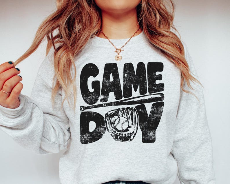 May include: A gray sweatshirt with the text "GAME DAY" in black with a baseball bat and glove graphic.