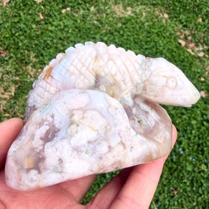 Puede incluir: Una taza de cerámica blanca con un asa negra y el texto "But first, coffee" en negro, con una fuente de estilo manuscrito. La taza está sobre una superficie blanca.