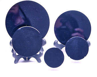 May include: A collection of dark blue, circular objects of varying sizes. The objects are arranged on small, black stands, creating a visually interesting display. The reflective surfaces suggest a polished finish.
