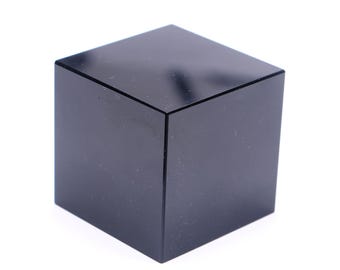Könnte beinhalten: Ein massiver schwarzer Würfel mit glatter, reflektierender Oberfläche. Der Würfel hat eine perfekte quadratische Form mit scharfen, sauberen Kanten. Das Objekt befindet sich vor einem weißen Hintergrund.