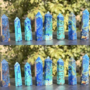 Peut inclure: Collection de huit obélisques en azurite, chacun présentant des motifs uniques de bleu profond et de turquoise. Les obélisques varient en taille et en forme, mettant en valeur les formations naturelles de la pierre. Fond vert flou.