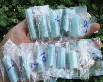 Könnte beinhalten: Eine Sammlung hellblauer Kristallstäbe, einzeln in klarem Kunststoff verpackt. Die Stäbe sind sechseckig und unterschiedlich groß. Einige Pakete haben blaue Zahlen. Der Hintergrund ist ein verschwommenes Grün.