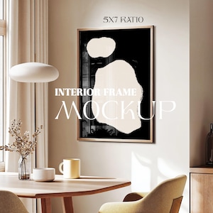 May include: A black and white abstract art print in a gold frame, hanging on a beige wall above a wooden table with a yellow chair. The text "INTERIOR FRAME MOCKUP" and "5X7 RATIO" are visible on the wall.