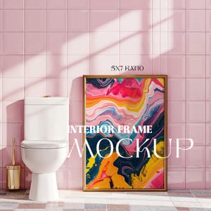 Puede incluir: Una maqueta de marco de imagen dorado con una pintura abstracta colorida en su interior. El marco está colgado en una pared de azulejos rosas en un baño con un inodoro blanco.