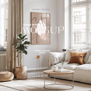 Pode incluir: Uma maquete de design de interiores de sala de estar com uma impressão de arte abstrata emoldurada com formas rosa e marrom e linhas pretas. A impressão está pendurada em uma parede branca acima de um sofá branco com uma almofada marrom. Uma mesa de centro de madeira com uma parte superior redonda fica na frente do sofá. Uma pequena planta em um vaso de madeira fica no chão ao lado do sofá. Uma pequena mesa auxiliar com uma parte superior dourada fica ao lado da planta. O texto "FRAME INTERIOR MOCKUP" está escrito em letras pretas na parede. O texto "WHITE INTUITION STUDIO" está escrito em letras pretas abaixo da moldura.