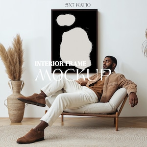Ingelijste poster Mockup met persoon. Man zit op een leunstoel. Verticale lijst 5 x 7. Zilveren lijst. Scandinavisch interieur. Downloadbare PSD. 043
