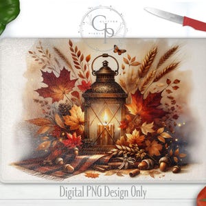 May include: A rectangular cutting board with a fall-themed design. It features a lantern with a lit candle, surrounded by autumn leaves, wheat, and acorns. The words "Digital PNG Design Only" are at the bottom. A red knife, tomatoes, and peppers are in the background.